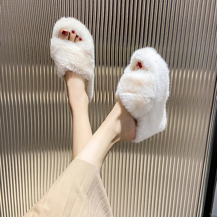 White fluffy slides on feet seen from above with red painted toenails
