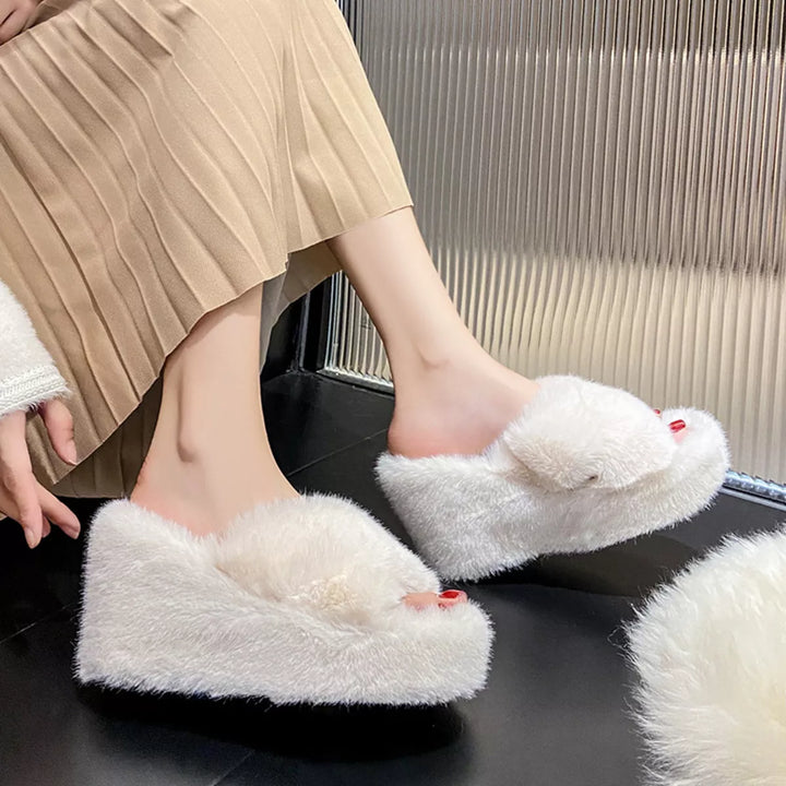 White fluffy wedge platform slides with crossed straps worn with a pleated skirt