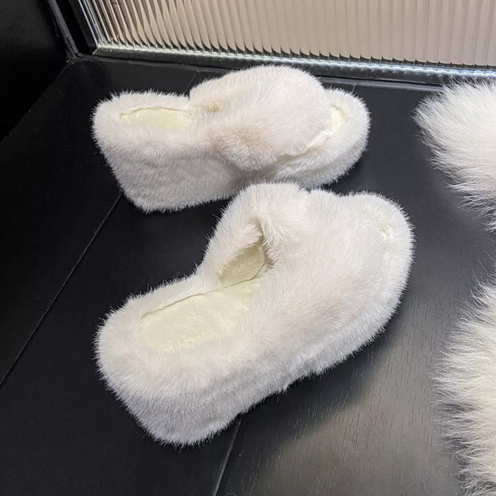 White crossed strap fluffy slippers from a high angle on a black surface