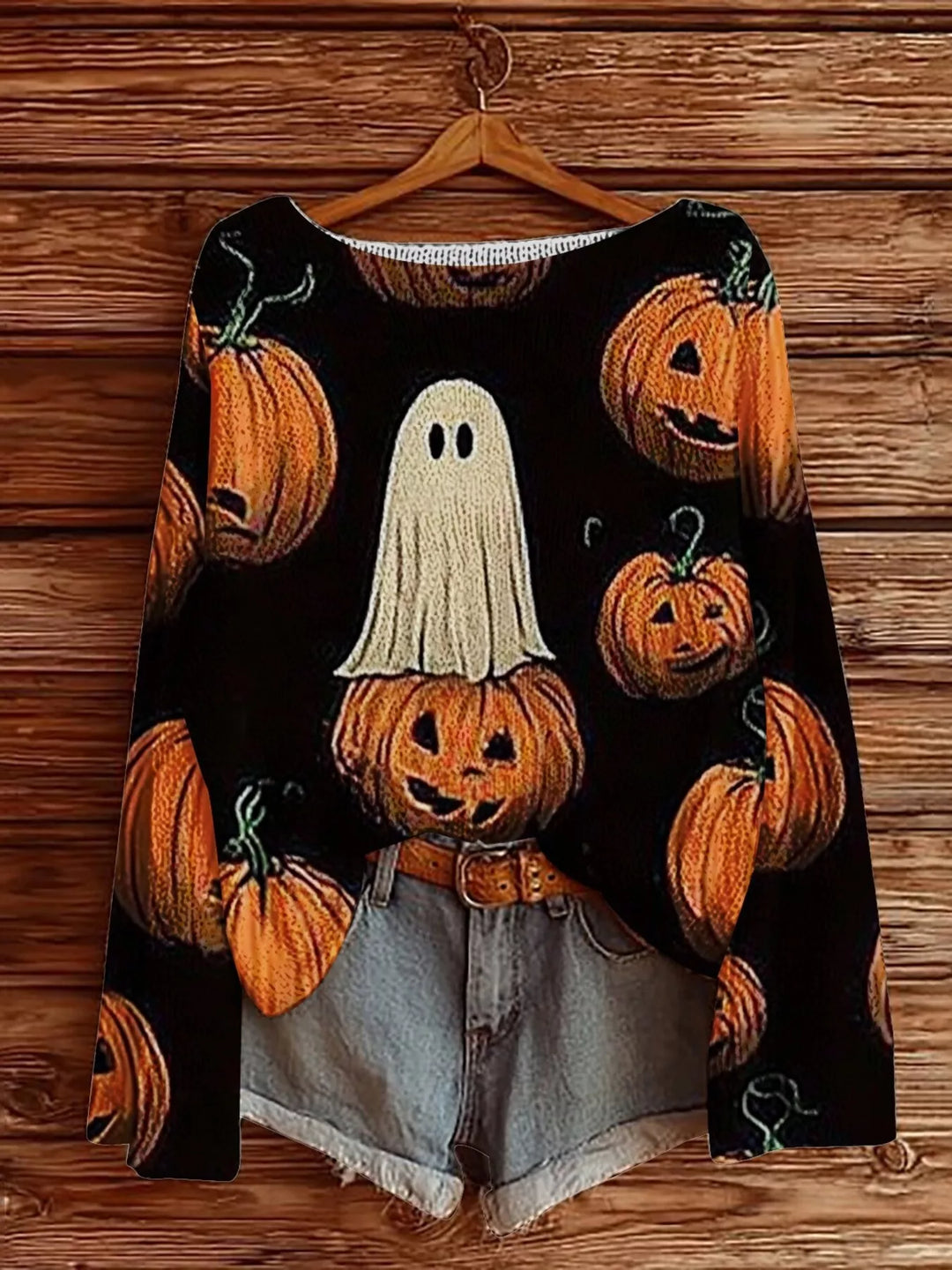Black Halloween sweater with ghost and pumpkin graphic hanging with denim shorts