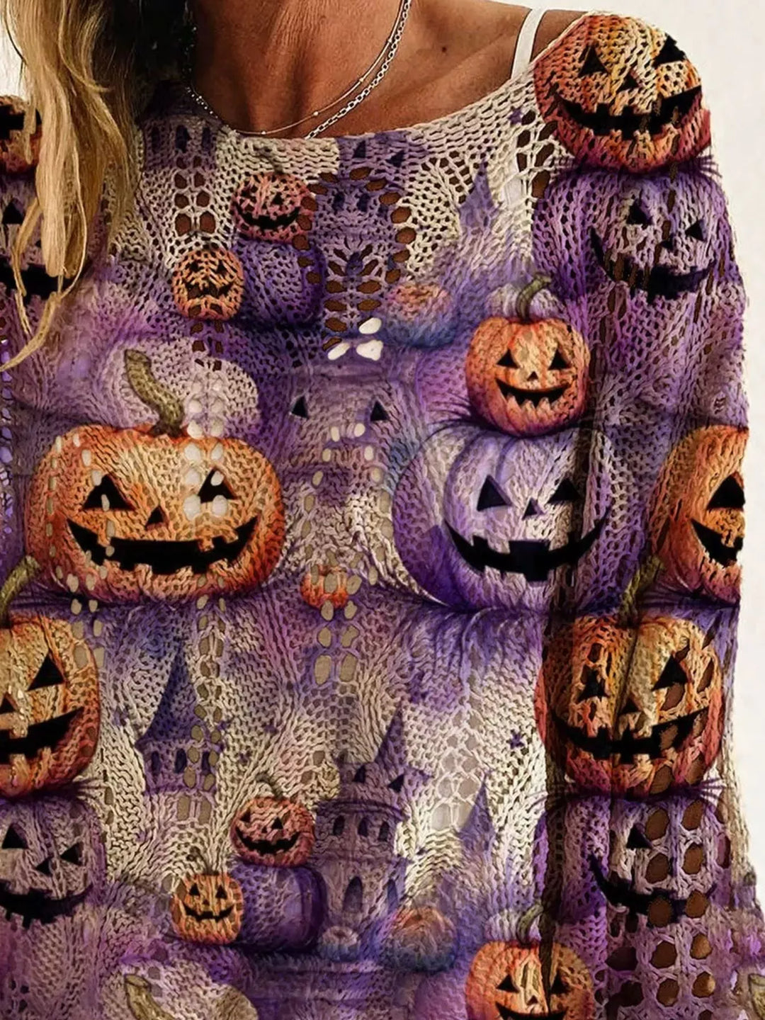 Close-up of the purple sweater print with grinning pumpkins and haunted castles