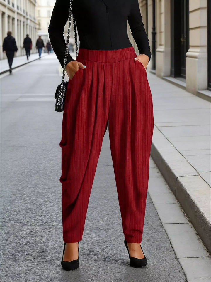 Burgundy pleated harem pants worn with a black long sleeve top and heels
