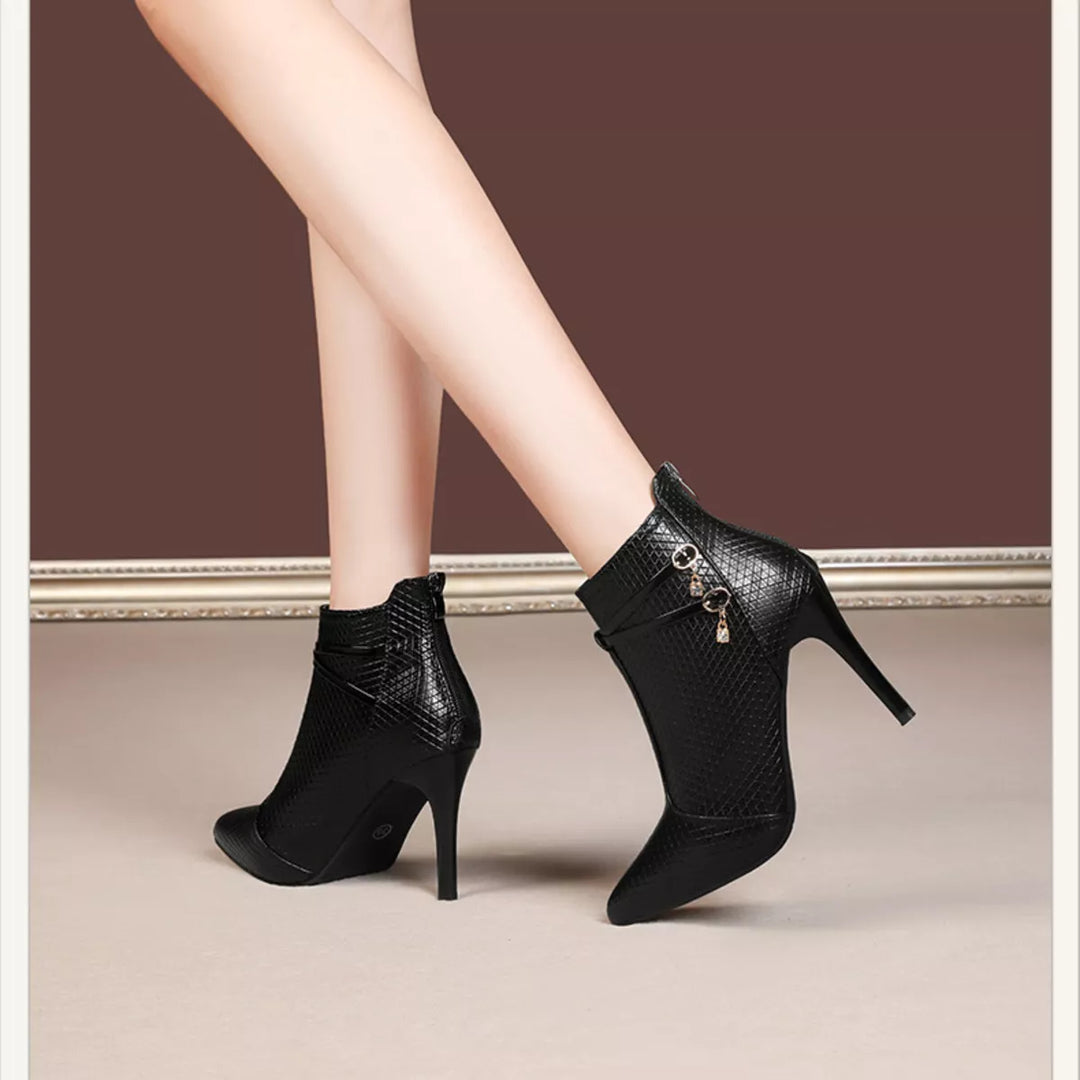 Black stiletto ankle boots seen from the back with zipper and charm detail