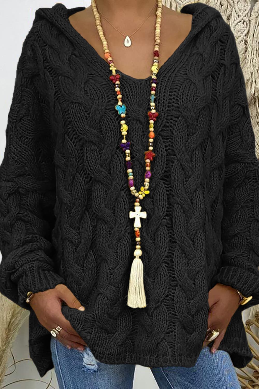 Close-up of the black cable knit hooded sweater with colorful beaded necklace