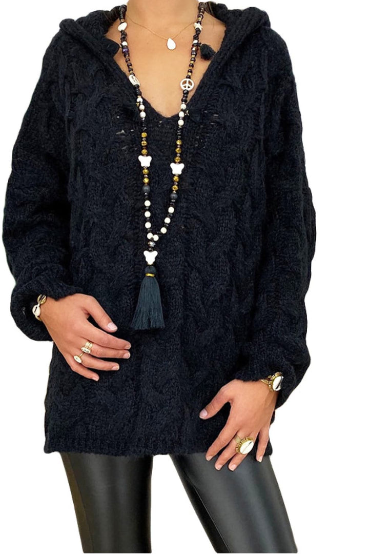 Black oversized cable knit hooded sweater with V neck, worn with leather pants