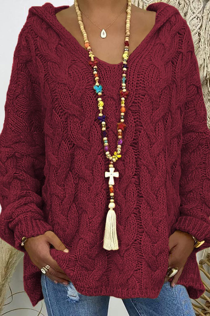 Close-up of the burgundy cable knit hooded sweater with V neck and long tassel necklace