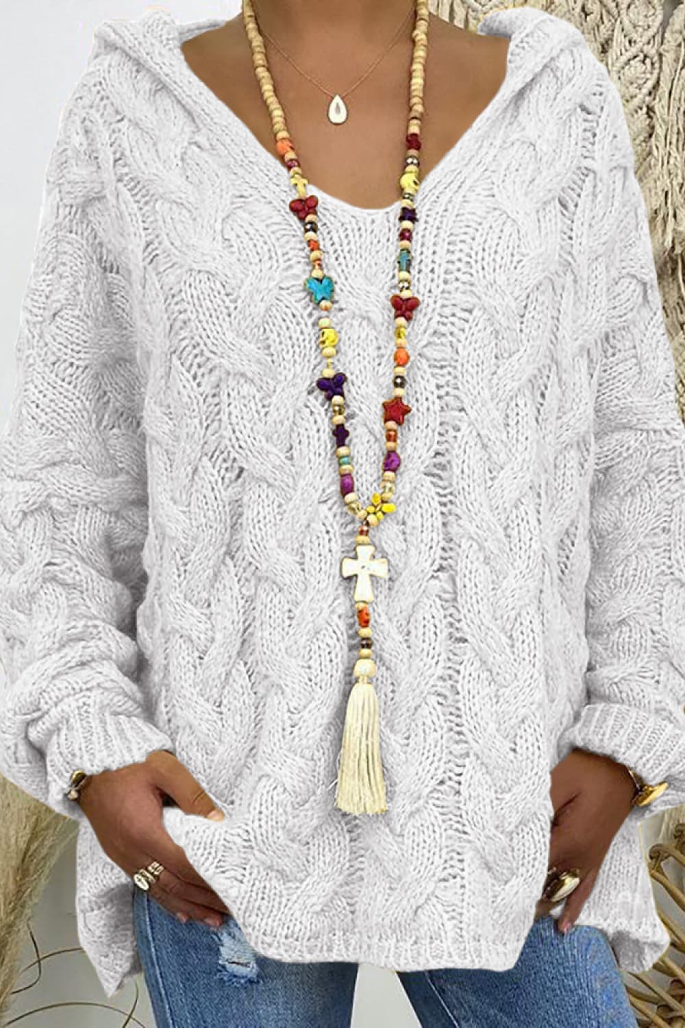 Close-up of the ivory hooded sweater with chunky cable pattern and bead necklace