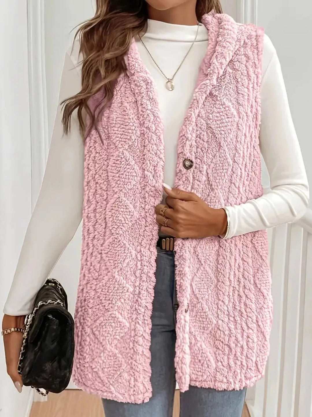 Blush pink hooded vest with cable knit pattern, front view with handbag