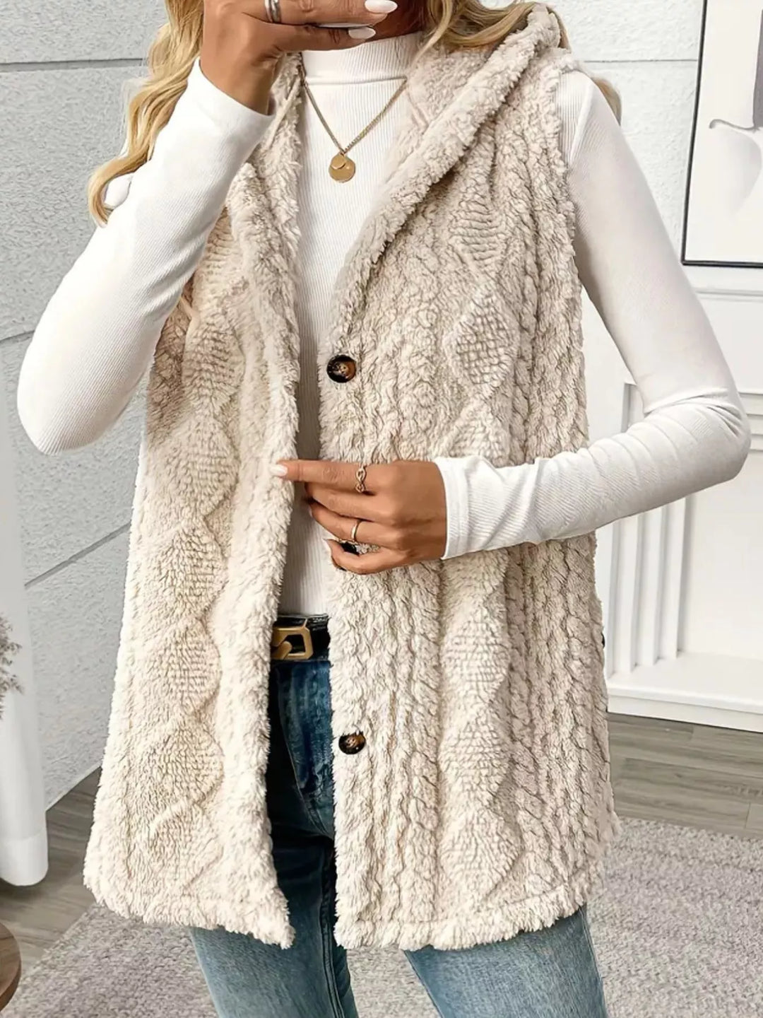 Cream fluffy cable knit vest styled with a white top and hand raised to the collar
