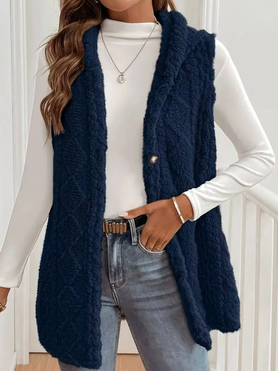 Navy hooded cable knit vest styled with jeans and a belt