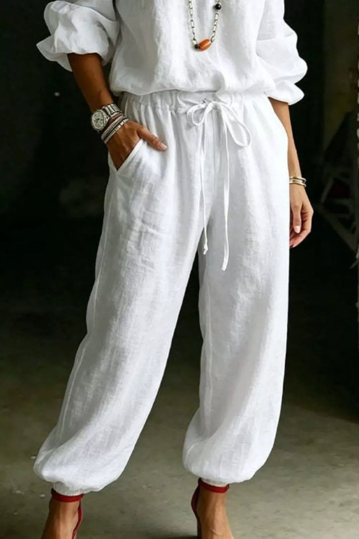 White jogger pants and off shoulder top, three quarter angle with hand in pocket