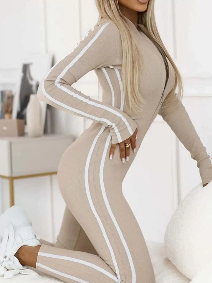 Beige striped jumpsuit with hand raised and white sneakers