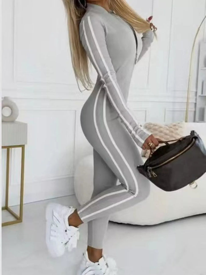 Gray long sleeve jumpsuit with white side stripes and a black belt bag