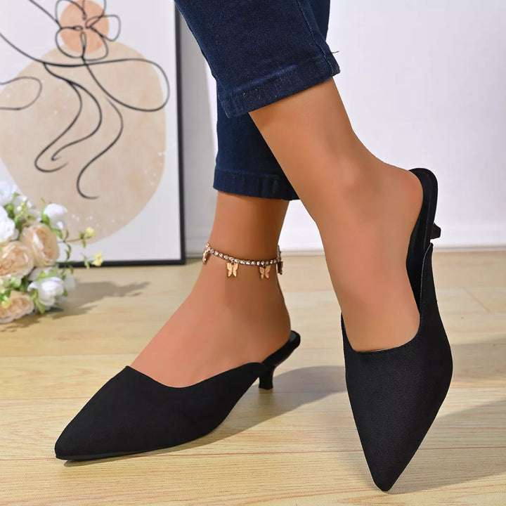 Black pointed toe kitten heel mules, side view with cuffed jeans