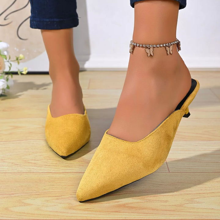 Mustard yellow slip on mules with a low heel, front angle