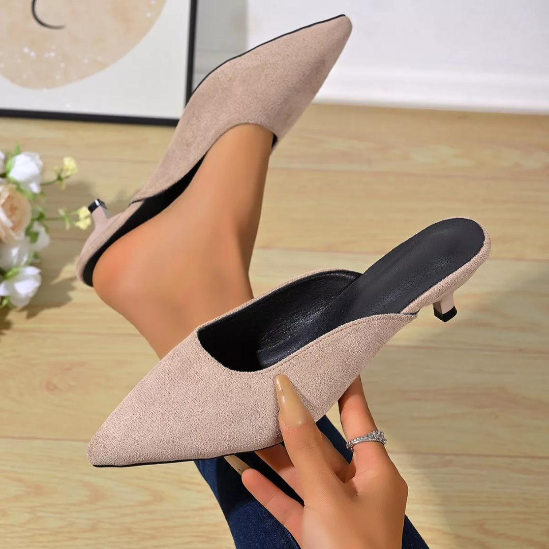Pair of taupe slip on kitten heel mules held in hand