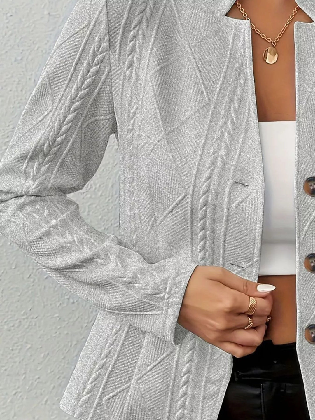Detail of the light gray knit blazer button front worn over a white top