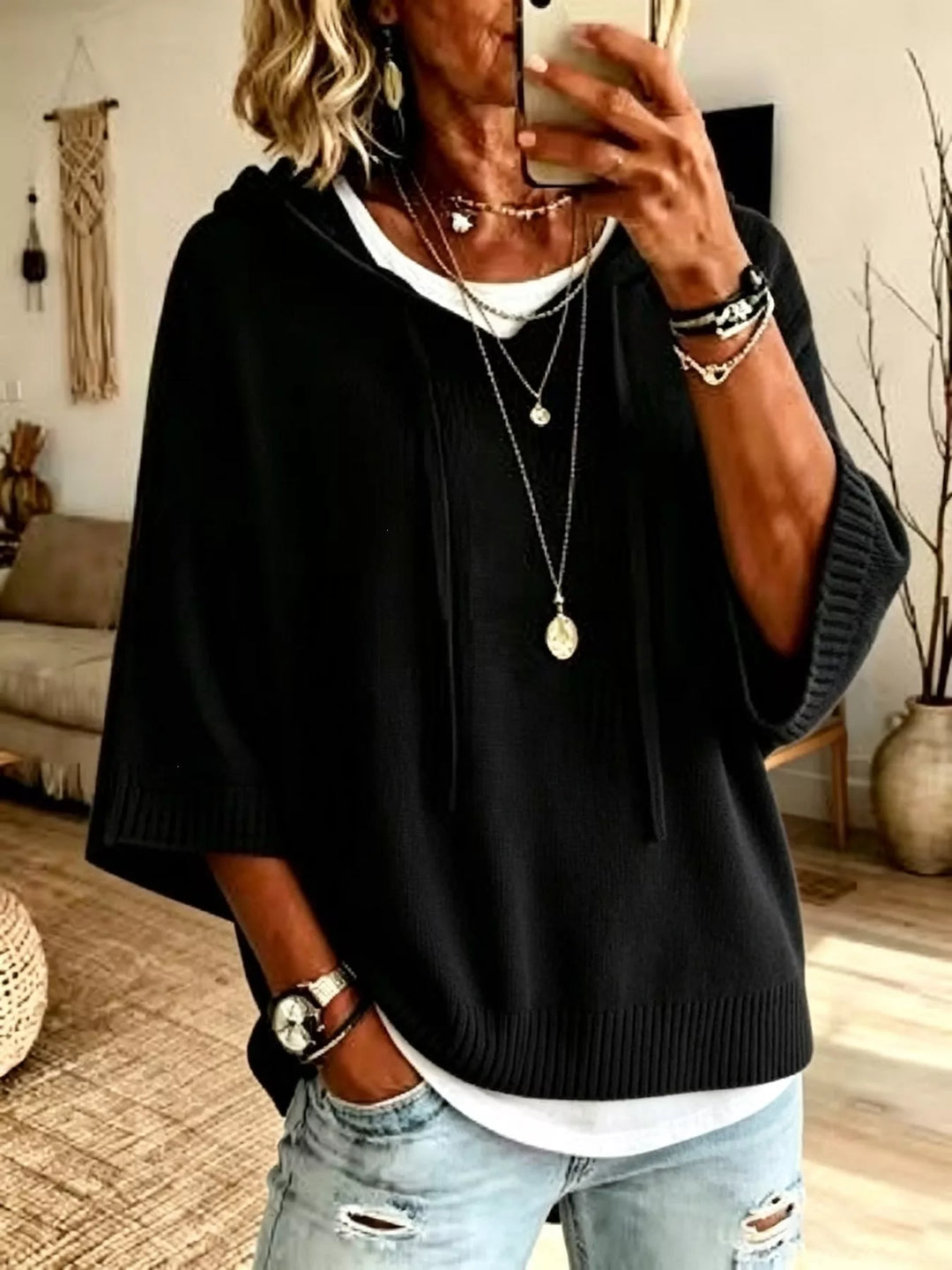 Black hooded knit sweater with drawstrings and batwing sleeves over a white tee