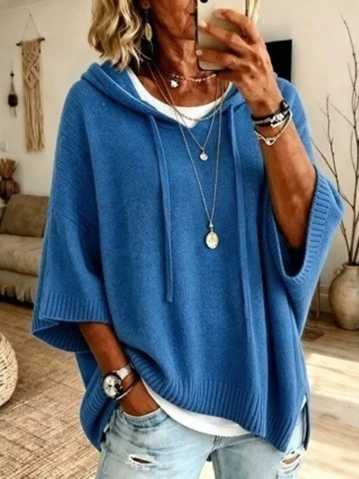 Blue hooded batwing sleeve knit sweater with drawstrings, worn over a white tee