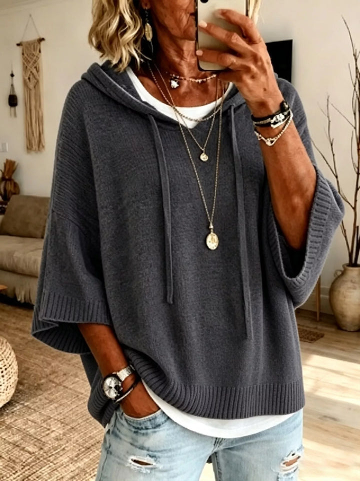 Charcoal hooded batwing sweater worn with a white layer and pendant necklace