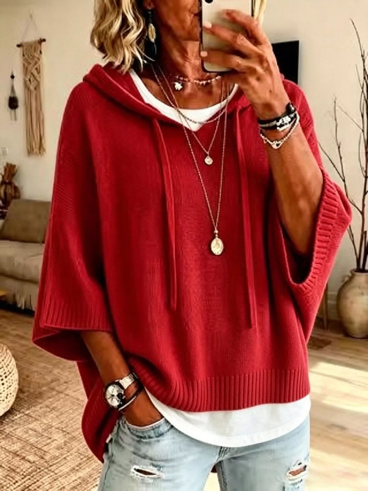 Red batwing sleeve hooded sweater styled with distressed jeans and a long necklace