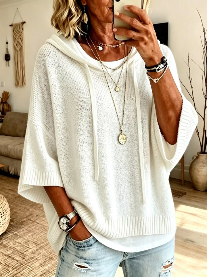 Women's knit sweater in white, hooded batwing sleeve with drawstrings, over jeans