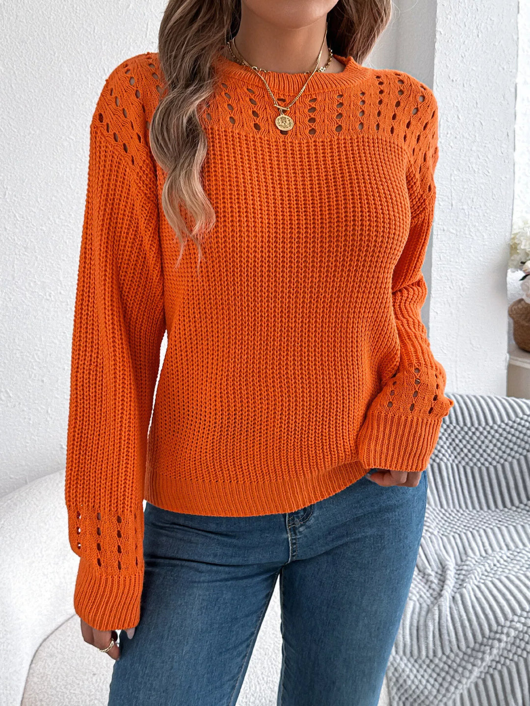 Orange round neck knit sweater with openwork yoke, front view with blue jeans