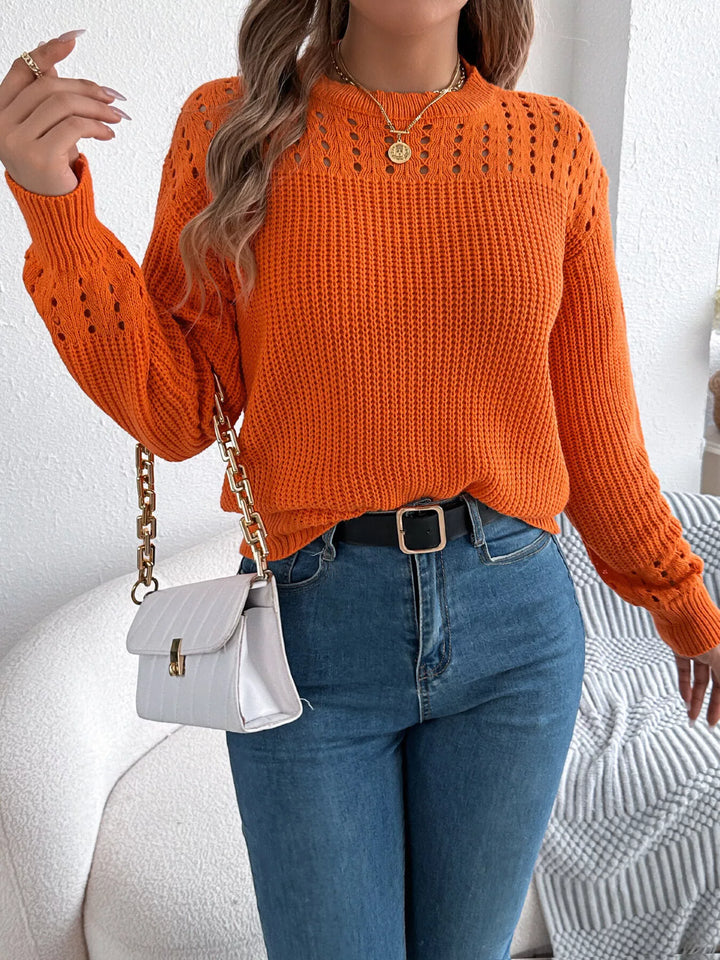 Orange knit sweater styled with a small white crossbody bag and jeans
