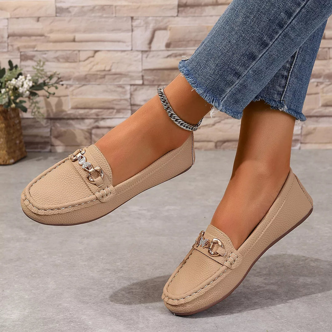 Women's loafers in beige, slip on moccasin flats with a gold-tone buckle, worn with jeans