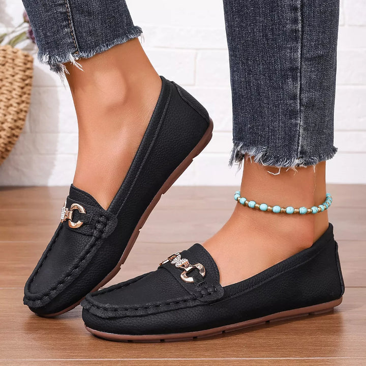 Black slip on loafers with a gold-tone buckle, worn with cropped jeans