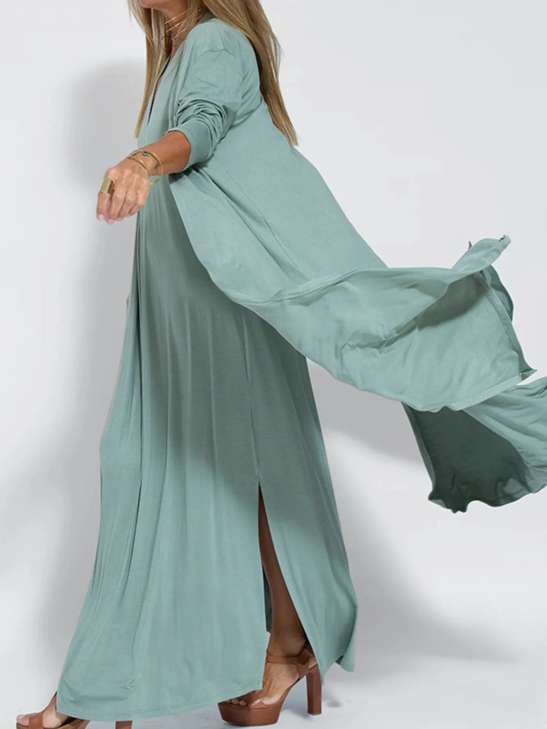 Sage green long cardigan flowing in motion, showing the side slit