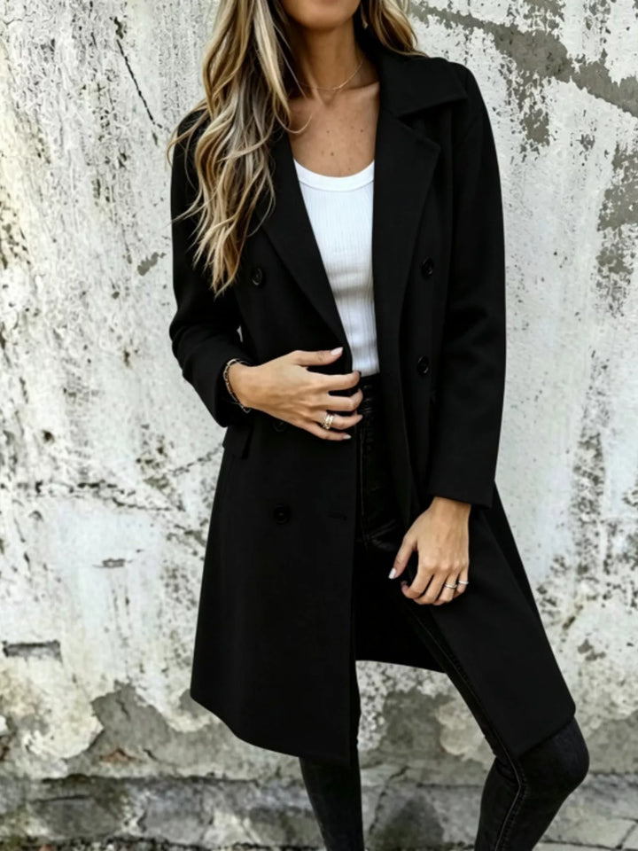 Black long coat with double breasted buttons, worn over a white top