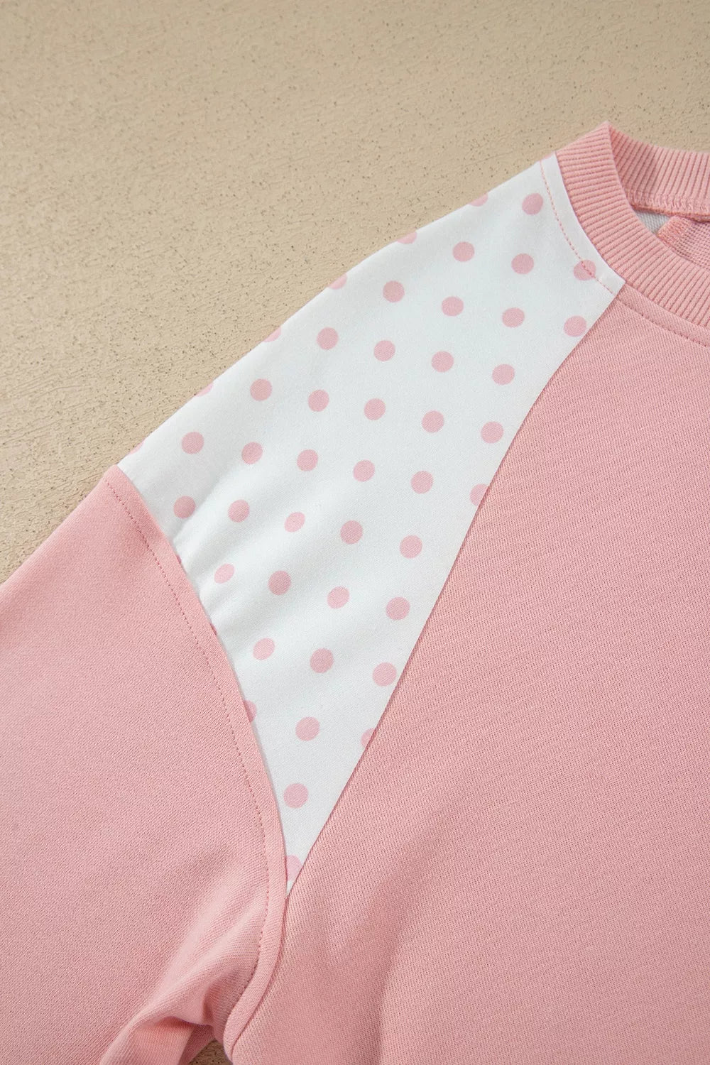 Close-up of the polka dot raglan sleeve panel on the blush sweatshirt