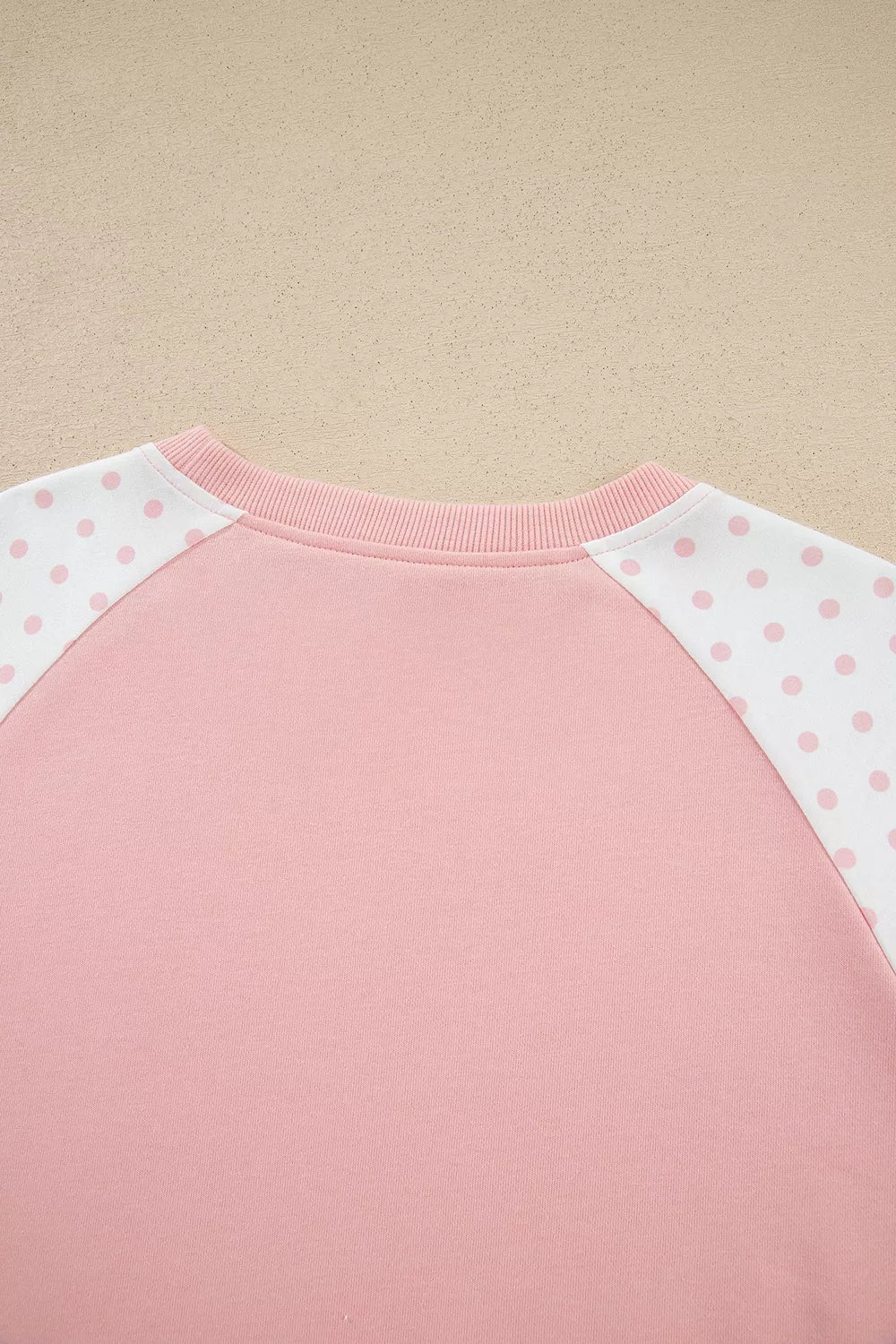 Detail of the blush sweatshirt neckline from the front with dotted shoulders