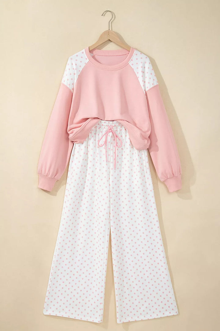 Blush cropped sweatshirt and polka dot pants hanging on a hanger