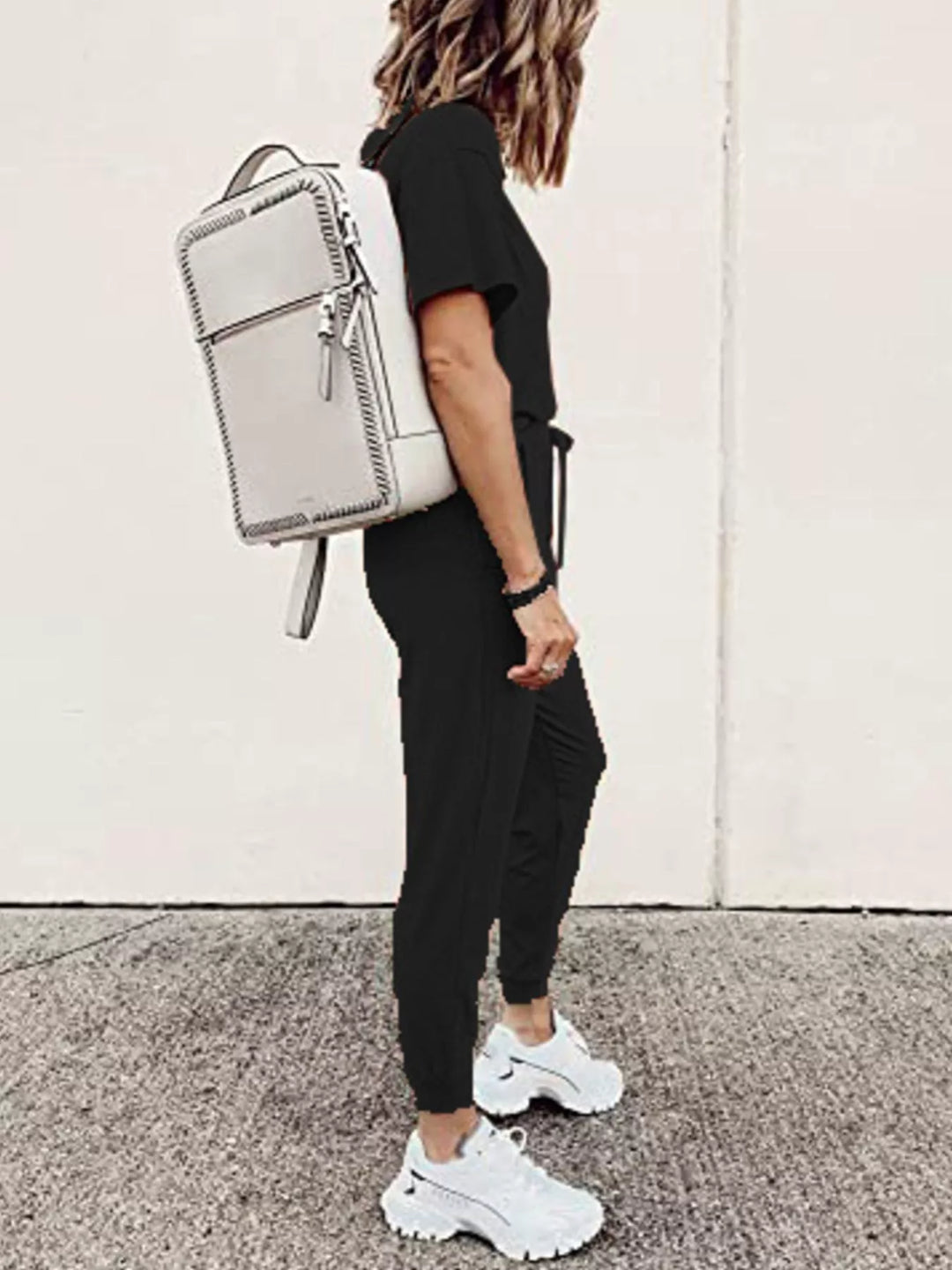 Black tee and jogger pants outfit from the side with a white backpack