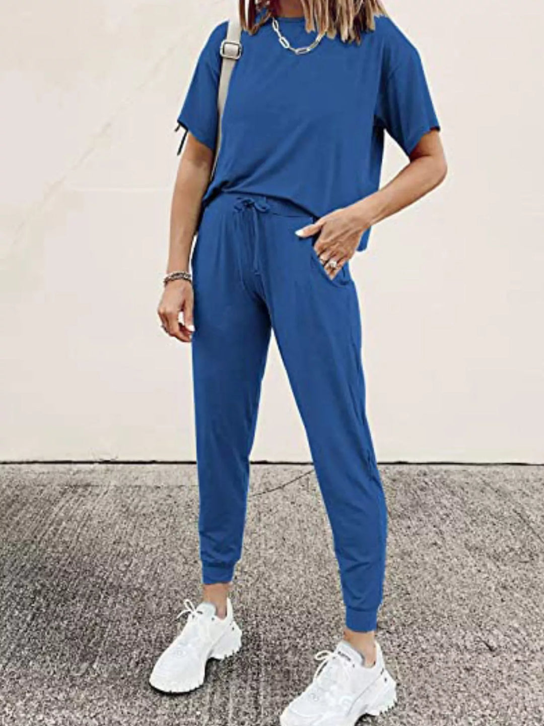 Royal blue tee and drawstring jogger pants, hand in pocket, white sneakers