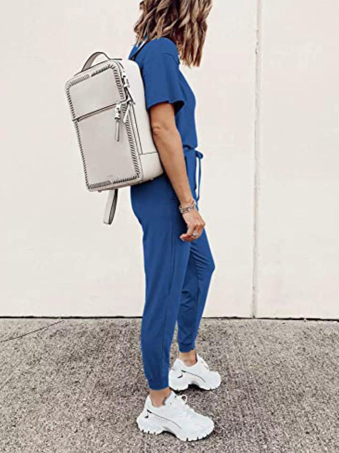 Royal blue jogger set side view with a white backpack on the shoulder