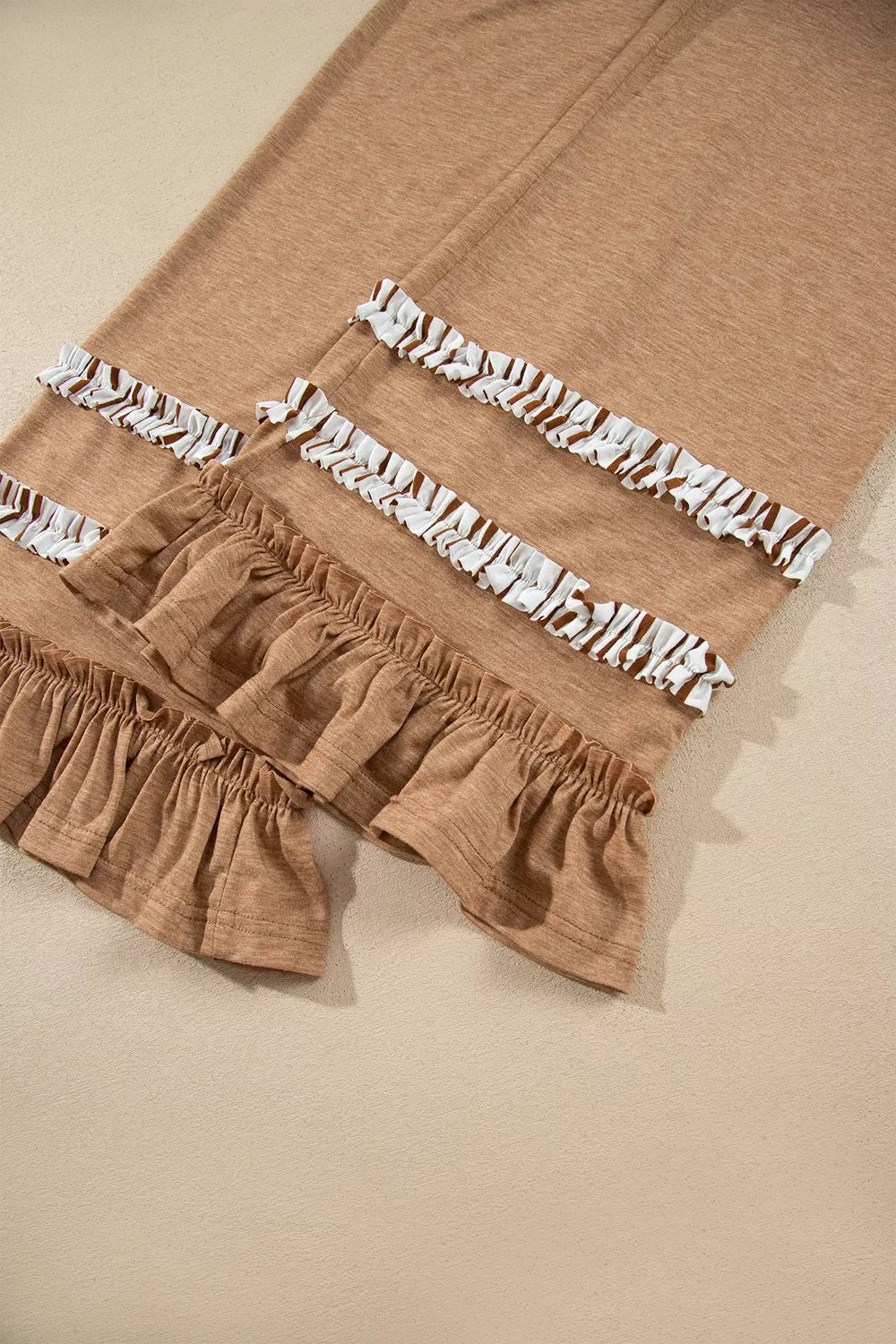 Close-up of the ruffled tiers at the hem of the camel wide leg pants