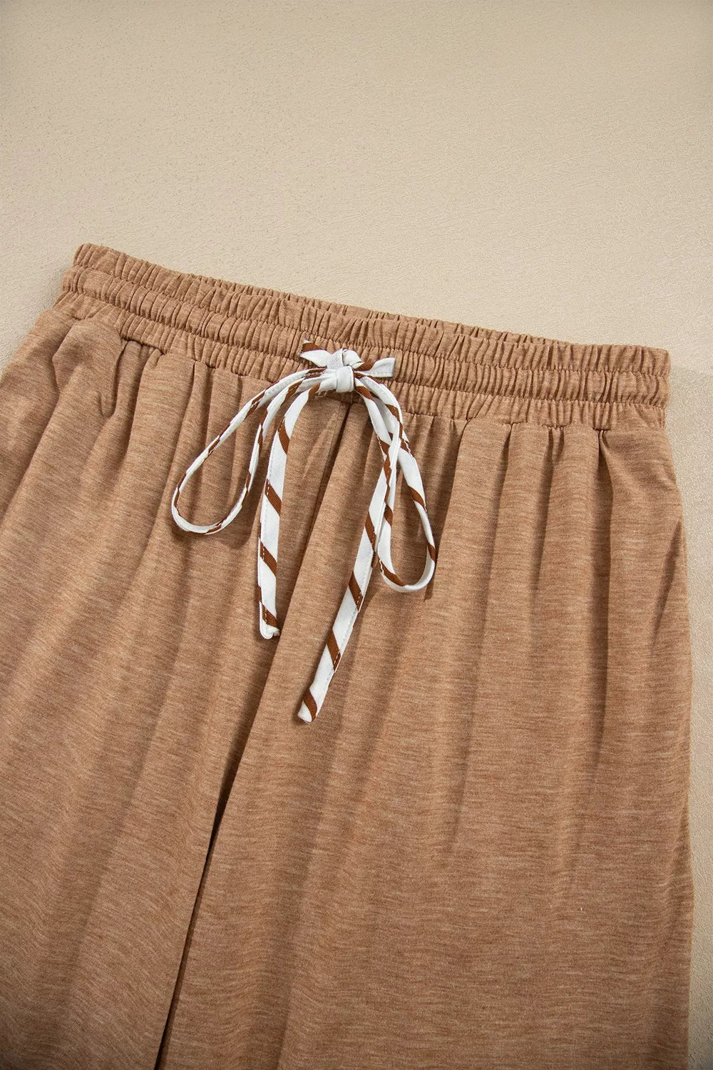 Detail of the camel wide leg pants elastic waist and striped drawstring