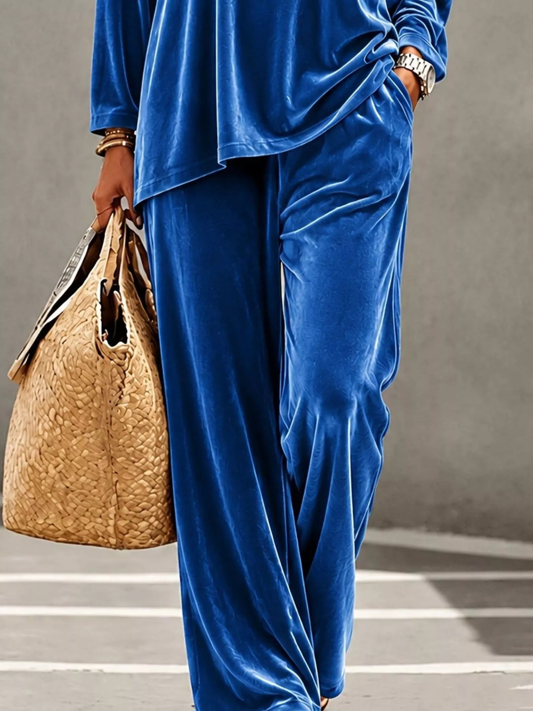 Blue velvet wide leg pants carried with a woven tote, cropped shot