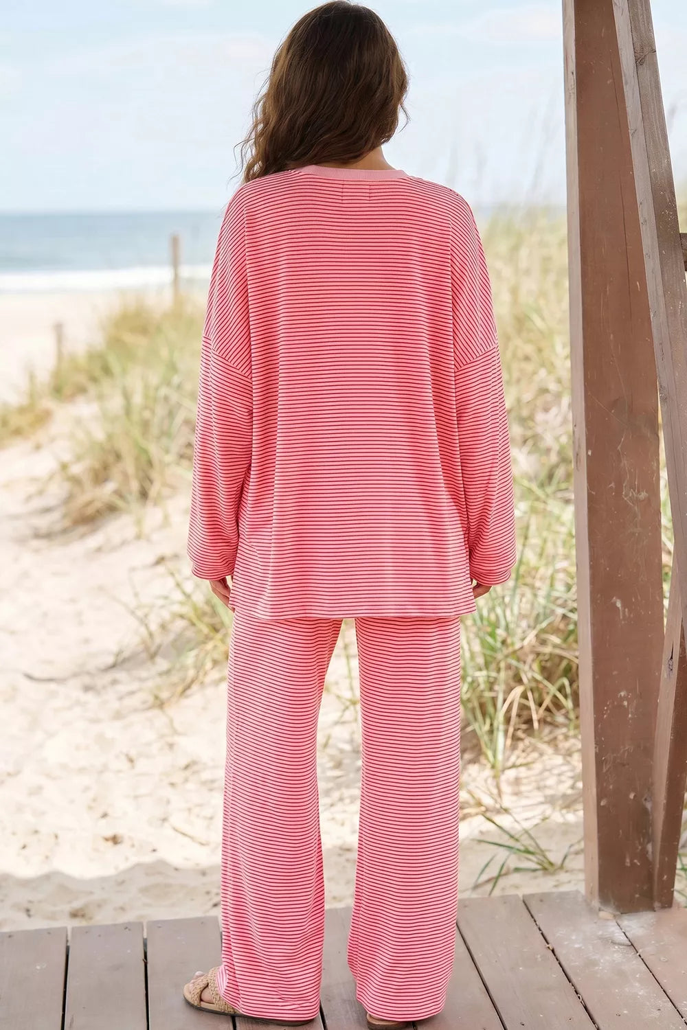 Back view of the dusty pink striped oversized top and wide pants on the beach