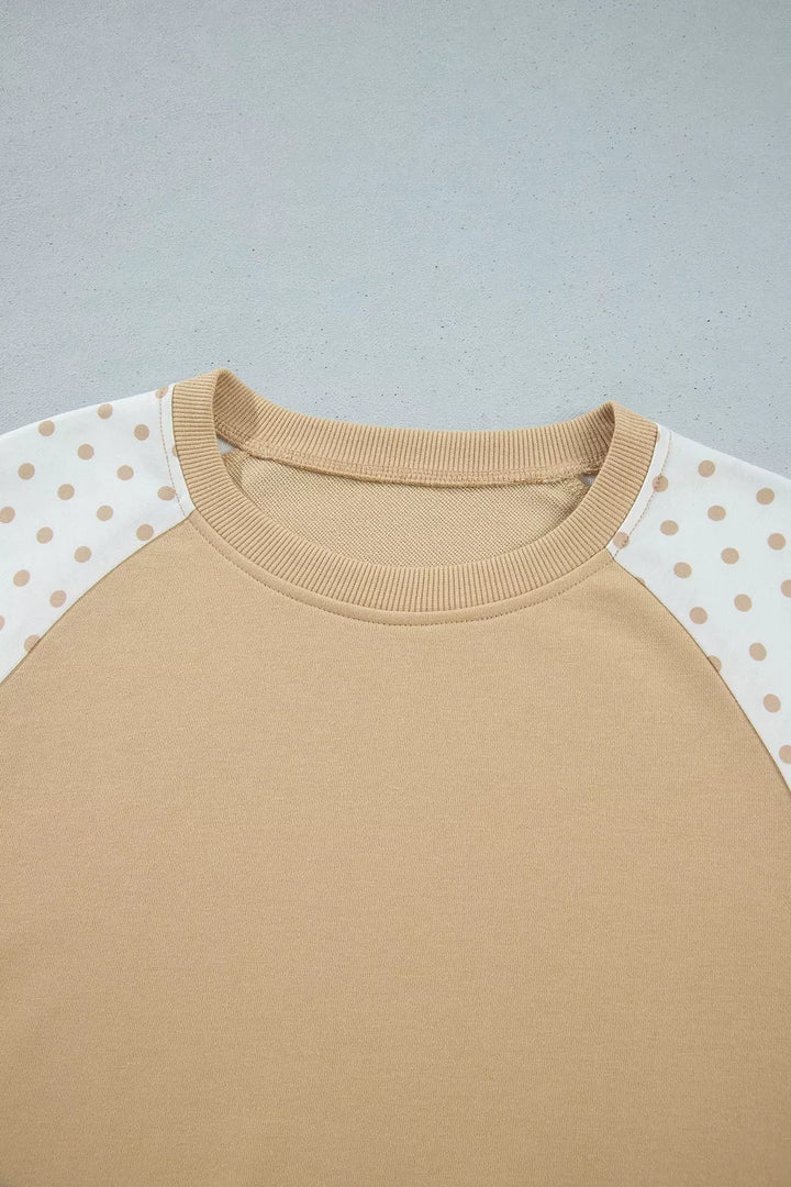 Close-up of the tan sweatshirt crew neckline and polka dot raglan sleeves