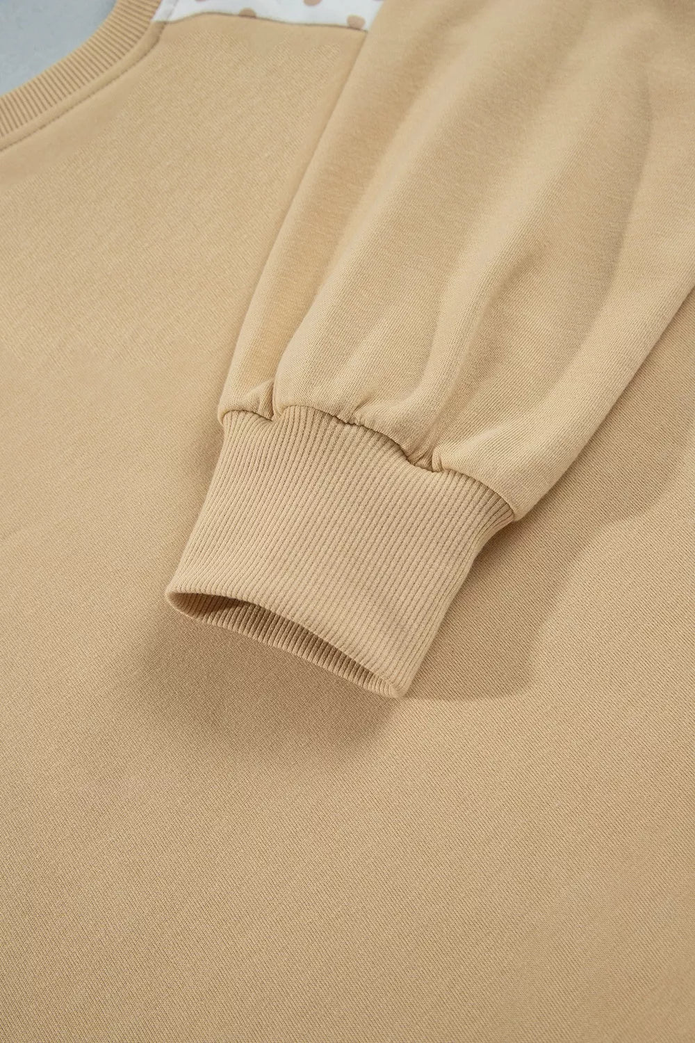 Close-up of the tan sweatshirt sleeve with ribbed cuff