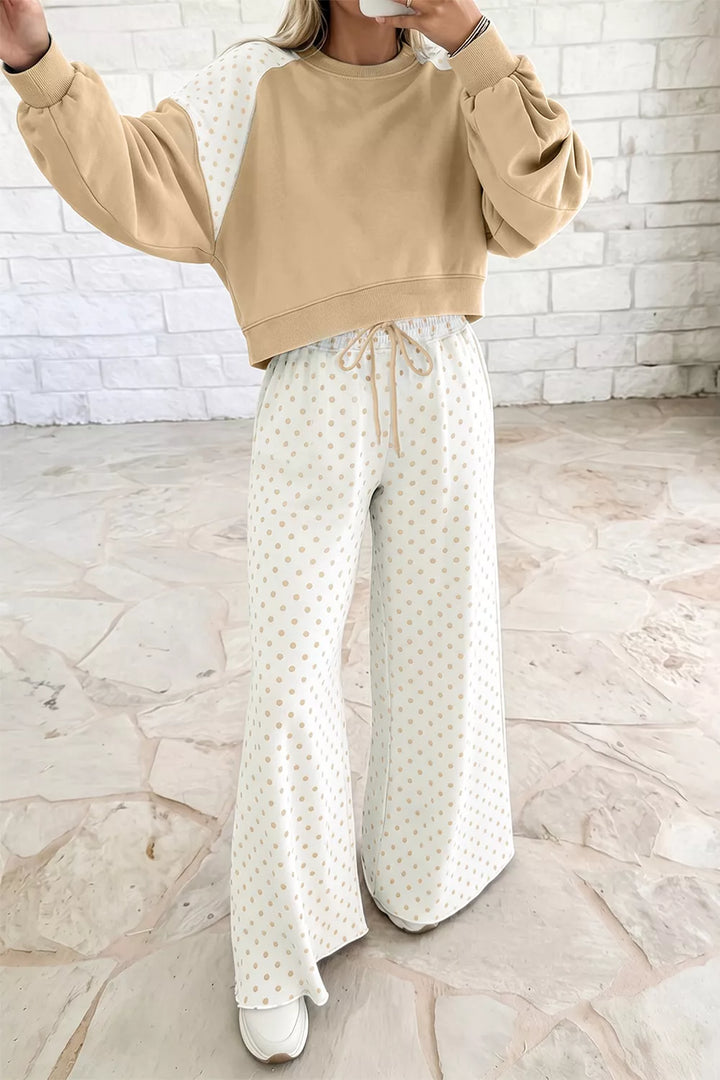 Tan cropped sweatshirt with raised arm, worn with polka dot pants on model