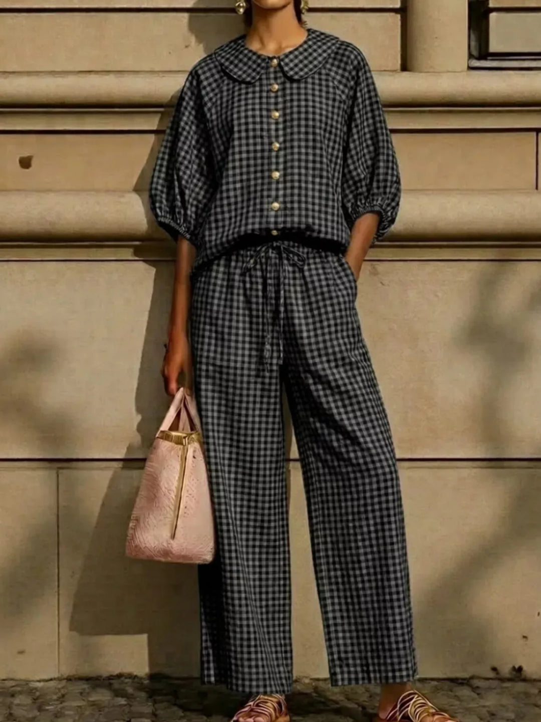 black gingham two piece set with puff sleeves standing against a stone wall
