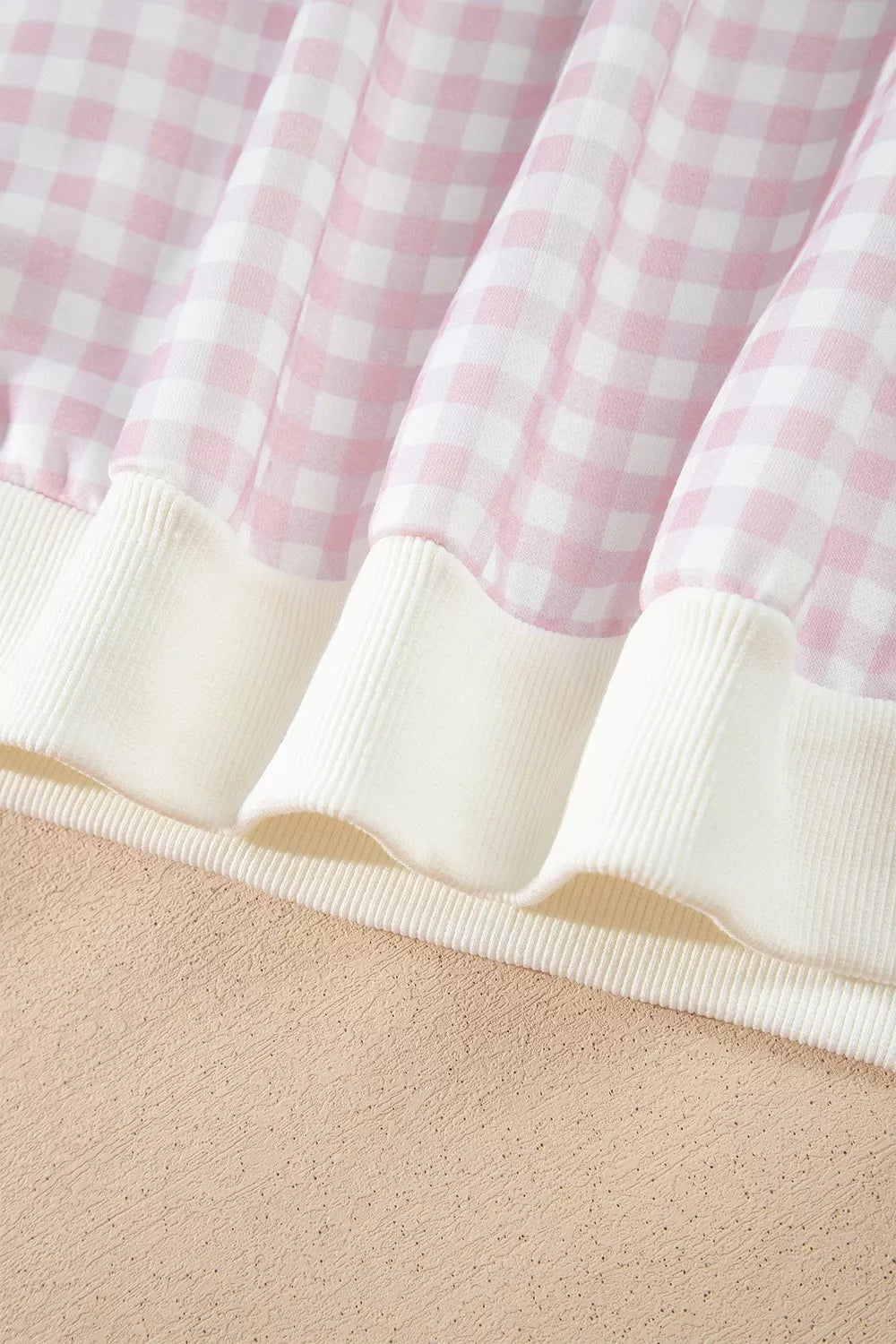 Close-up of the ribbed hem on the blush pink gingham sweatshirt