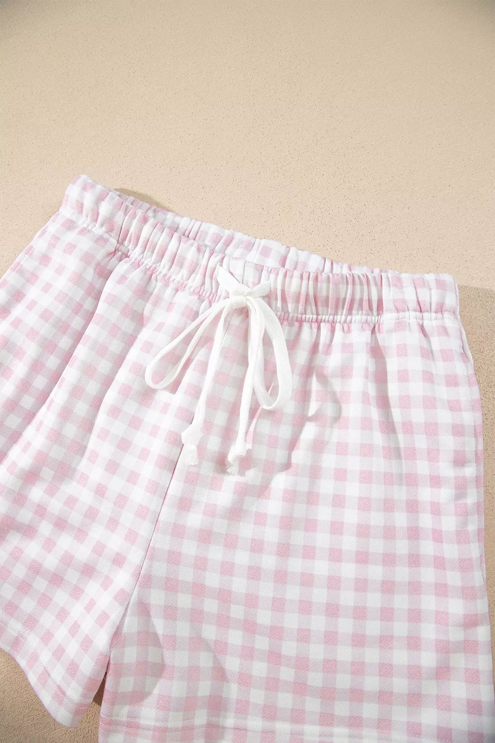 Gingham shorts waistband with a white drawstring, laid flat