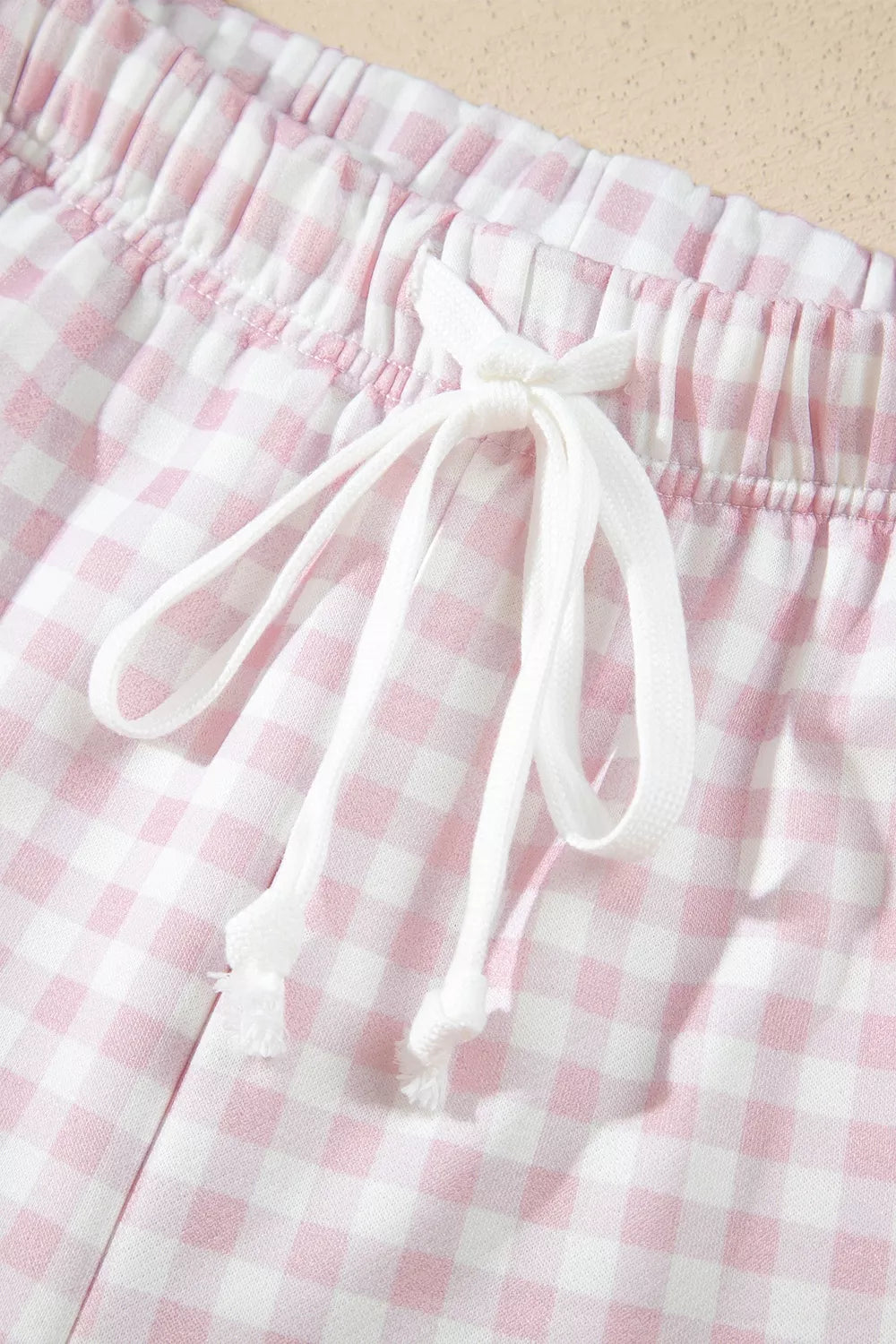 Close-up of the drawstring knot and elastic waist on the gingham shorts