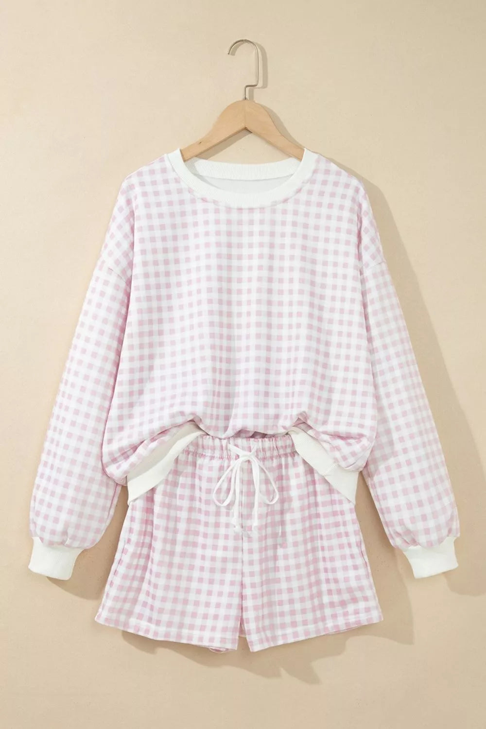 Blush pink gingham sweatshirt and shorts hanging together on a hanger
